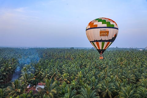A hot air balloon floats over picturesque Pollachi